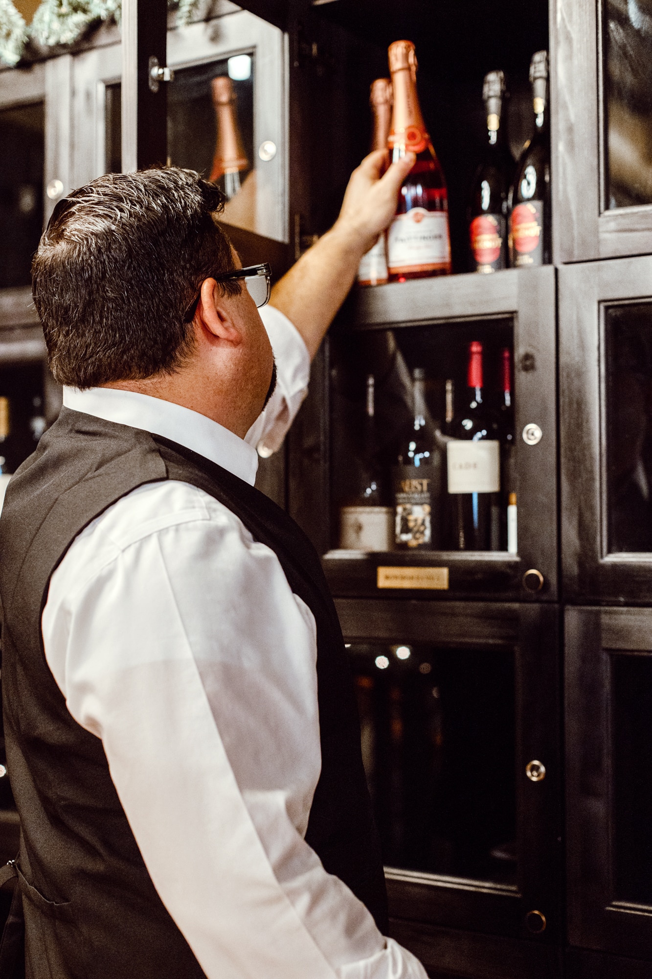 Bowdie's staff selecting wine from a cabinet
